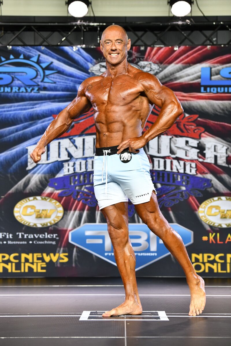 Alan Scott posing on stage at a bodybuilding competition